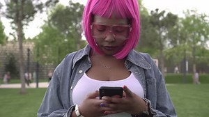 Une jeune femme africaine noire attrayante aux gros seins utilise un smartphone
