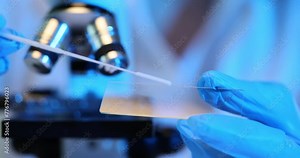 Scientist analyzes sample under a glass microscope