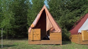 Tents with wooden bases and canvas roofs at a scout camp in the summer nature. Outdoor recreation.