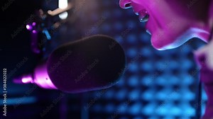 Beautiful young girl dj speaks into microphone, records podcast or morning news show for radio. Close up of podcast presenter or DJ talking on the microphone. Wears professional headphones