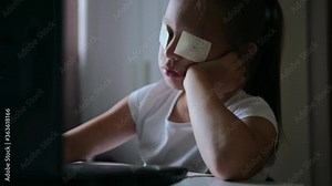 Cute smart elementary school child girl doing math homework sits at home behind a laptop, adorable pretty little school child studying alone making notes, children primary education concept. The child