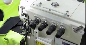 Four-thread overlock sewing machine. Female hands, working on tailoring. Automatic industrial sewing machine for textiles. Production of knitwear.