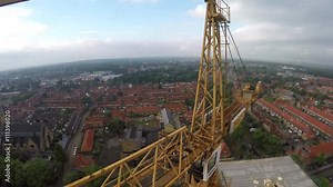 Aerial bird view of tower building crane stunt drone fly through and construction site building apartments real estate from helicopter cockpit view of new houses city town cloudy sky background 4k