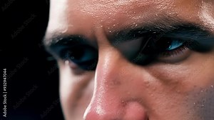 Determined male athlete sweating and training intensely in a dark gym, showing strength and focus. His eyes reflect motivation and commitment, highlighting the importance of an active lifestyle