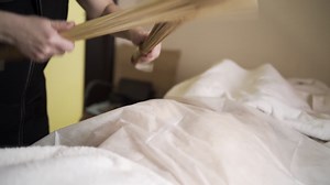 Female masseuse working with woman and performing Japanese massage with bamboo sticks in a spa salon. Action. People, beauty, healthy lifestyle and relaxation concept.