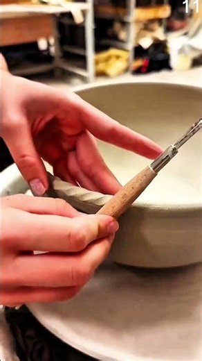 Trimming textured clay bowl rim with handheld tool