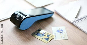 A compact and portable card scanner is displayed with various ID cards and stationery items on a wooden surface