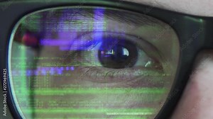 Close up view of a coding text reflecting on the glasses in green color with blue highlights in the matrix style.