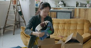 Asian Female Packing Clothes in boxes.