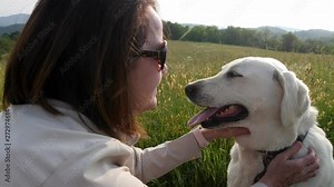 Woman plays with white lab dog with mountain backdrop