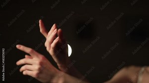 A graceful ballerina dancing ballet elements in the dark with light on the background, slow