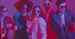 Happy crowd of dancers is seen dancing together under neon lights, wearing colorful costumes. The vibrant atmosphere, pulsating music, and energetic dance moves create a lively party scene.