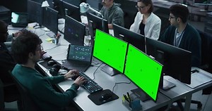 Team of Young Professionals Working in a Technological Research and Development Agency. Software Programmer Working on a Computer with Two Green Screen Mock Up Displays. Elevated High Angle Footage
