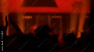 Super slow motion: people crowd partying, cheering, raising hands up and clapping at rock concert in front of stage of nightclub. Bright colorful stage lighting. Nightlife and entertainment concept