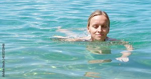Beautiful woman swimming in the clear water ocean.