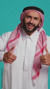 Vertical video Person wearing customary thobe and kufiyah seems joyful, exhibiting genuine muslim beliefs and practices. Middle eastern guy with distinctive culture, dress and structured scarf.