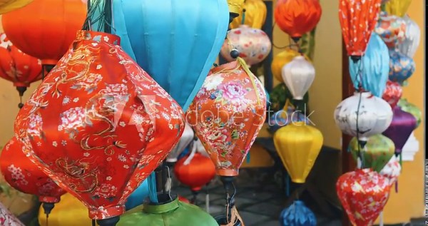 Traditional vietnamese silk lanterns are hanging in various colors and patterns, creating a vibrant display in the historic streets of hoi an