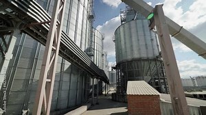 Large metal silo for storing grain. Modern industrial plant. Granary. Silver containers storing agriculture crop. Grain elevators on nature background. Silo Grain Tank Granary Elevators.