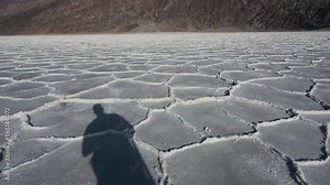 Tourist waving in Death Valley salt flats at the hottest Badwater region of the National Park.