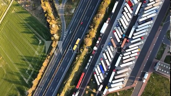 cargo yard overview, transport hub with organized trucks, overview of logistics area with trucks and greenery, high vantage shot of freight yard featuring vehicle alignment and surrounding