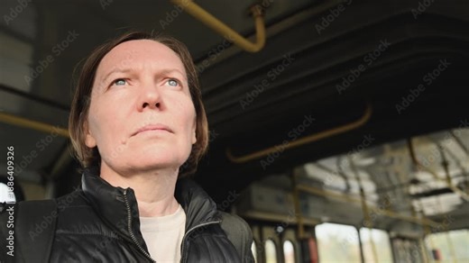 Adult brunette woman standing inside public bus during daily commute, urban transportation scene. 4K.