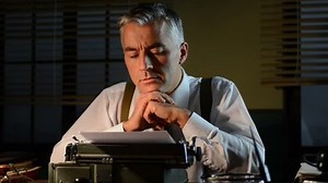 Vintage 1950s reporter working at desk with typewriter and waiting for inspiration.