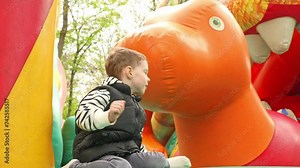 Child jumping on colorful playground trampoline. Kids jump in inflatable bounce castle on kindergarten birthday party Activity and play center for young child. Little boy playing outdoors in summer.