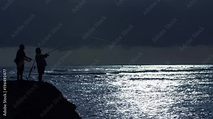Fishermen cast at a cool blue sunset at Ala Moana Beach Park in Honolulu, Hawaii