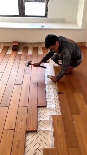 a professional craftsman installs wood flooring in a room using a hammer