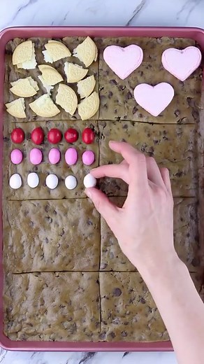Valentine’s Cookie Tray for a Crowd 🍪💖 The best kind of cookie is the one you can share, and this one has ALL the goodies! 😍 INGREDIENTS -Tollhouse chocolate chip cookie dough -golden Oreos -marshmallows hearts -pink M&M’s -ghirardelli strawberry squares -chocolate hearts -Twix bars -reeces cups -Valentine’s animal crackers Press the cookie dough onto a baking sheet and divide into 8 equal pieces. Place the candies onto each square and place into a preheated oven at 300F to bake for about 25 