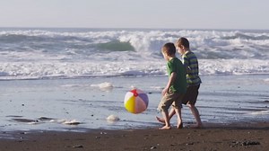 Two boys playing with beach ball, slow motion