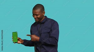 Smiling security guard working protection job presenting mockup smartphone, studio backdrop. Portrait of upbeat bodyguard showcasing green screen phone, isolated over studio background