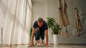 adult man with a beard doing exercises for stretching the muscles of the body doing sports yoga active lifestyle trainer in his own studio