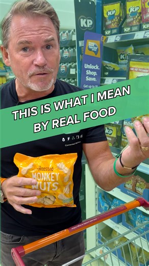 Monkey nuts. Peanuts in their shells. One ingredient. Now look at the packet next to it. Roasted and salted nuts. Sounds healthy enough, right? Check the ingredients. Peanuts, vegetable oil, sugar, salt, flavourings. Sugar in nuts. Think about that for a moment. They took a perfectly healthy food and added sugar to it. Why? Because sugar is addictive. It makes you eat more. It makes you buy more. The food industry does this constantly. Takes real food, processes it, adds sugar and seed oils, the