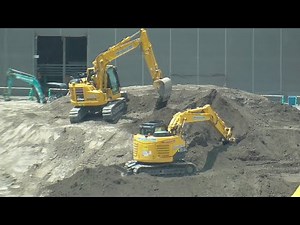 A hydraulic excavator digs dirt at a construction site.