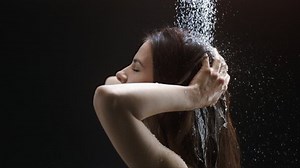 Beautiful woman head showering shampoo rinse in slow Motion. head of a woman close up rinsing out shampoo under shower on black background