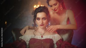 Two women vampires. beauty woman Fantasy lady evil face vampire queen girl biting victim neck drinking blood with sharp fangs teeth red lips makeup close-up. dark night room gothic old style art 4k