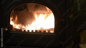 Blazing fire in vintage cast iron potbelly stove with semicircular door. Flame in antique fireplace of retro style interior. Cozy winter background