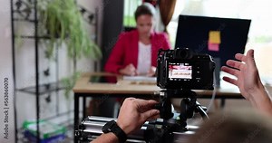 A digital camera takes a woman sitting at a table in an office
