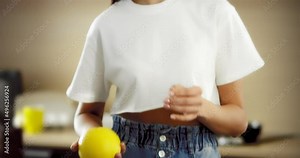 Cheerful young woman throwing a grapefruit in the kitchen tossing it up. Asian woman with a beautiful smile holds a citrus fruit. The concept of proper nutrition.