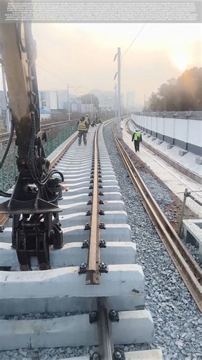 Excavator pushes steel rails along the track.
