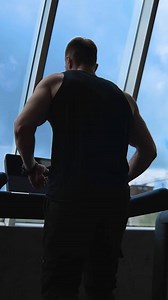 Fitness man athlete training using treadmill. Sportsman doing intense cardio workout challenge enjoying running practice in gym. Slow motion. Back view. Vertical