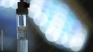 IV (infusion) bags and bottles hanging on poles during a real surgery going on in the background. Patient, illness, treatment, anesthesia, hospital, medicine and healthcare symbolism and concept.