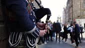 Close-up midsection of a man playing Scottish bagpipes, street...