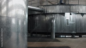 Fermentation tanks, Brewery equipment, Modern equipment. Sleek metal fermentation tanks and piping in modern industrial brewery setting.