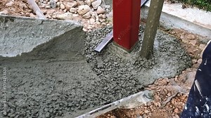 The worker is tamping a poured concrete. Compaction of the cement mixture. Pouring wet concrete from a mixer truck into a pit with pillar. Foundational work. Building industry. High quality 4k footage
