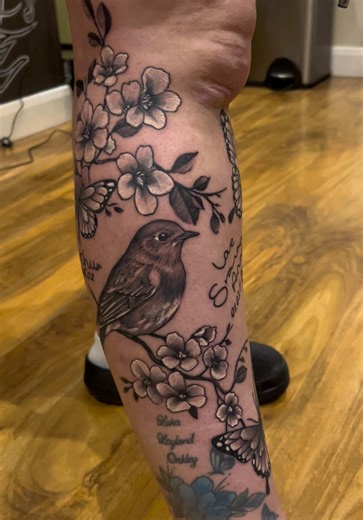 Carried in wings and blossoms. A memorial tattoo honoring loved ones, with names and dates forever held in ink. Always remembered. #MemorialTattoo #InLovingMemory #BirdTattoo #FloralTattoo #TattooWithMeaning
