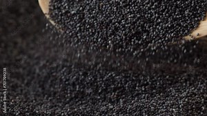 poppy seeds falling into a pile from a wooden spoon, slow motion. opium poppy macro.poppy seed harvest