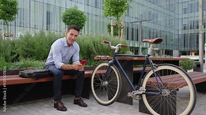 Man with bicycle using red cell phone app outside the office Stock Video