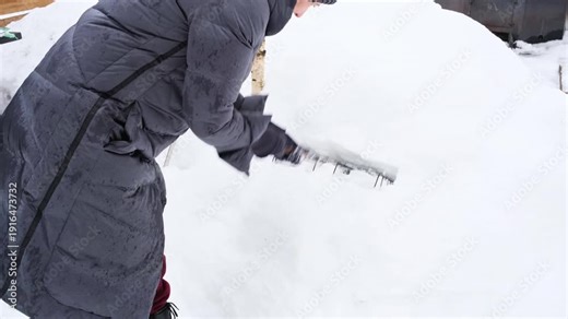 Woman using snow as natural cleaner, moving grill grate up and down inside snowbank.